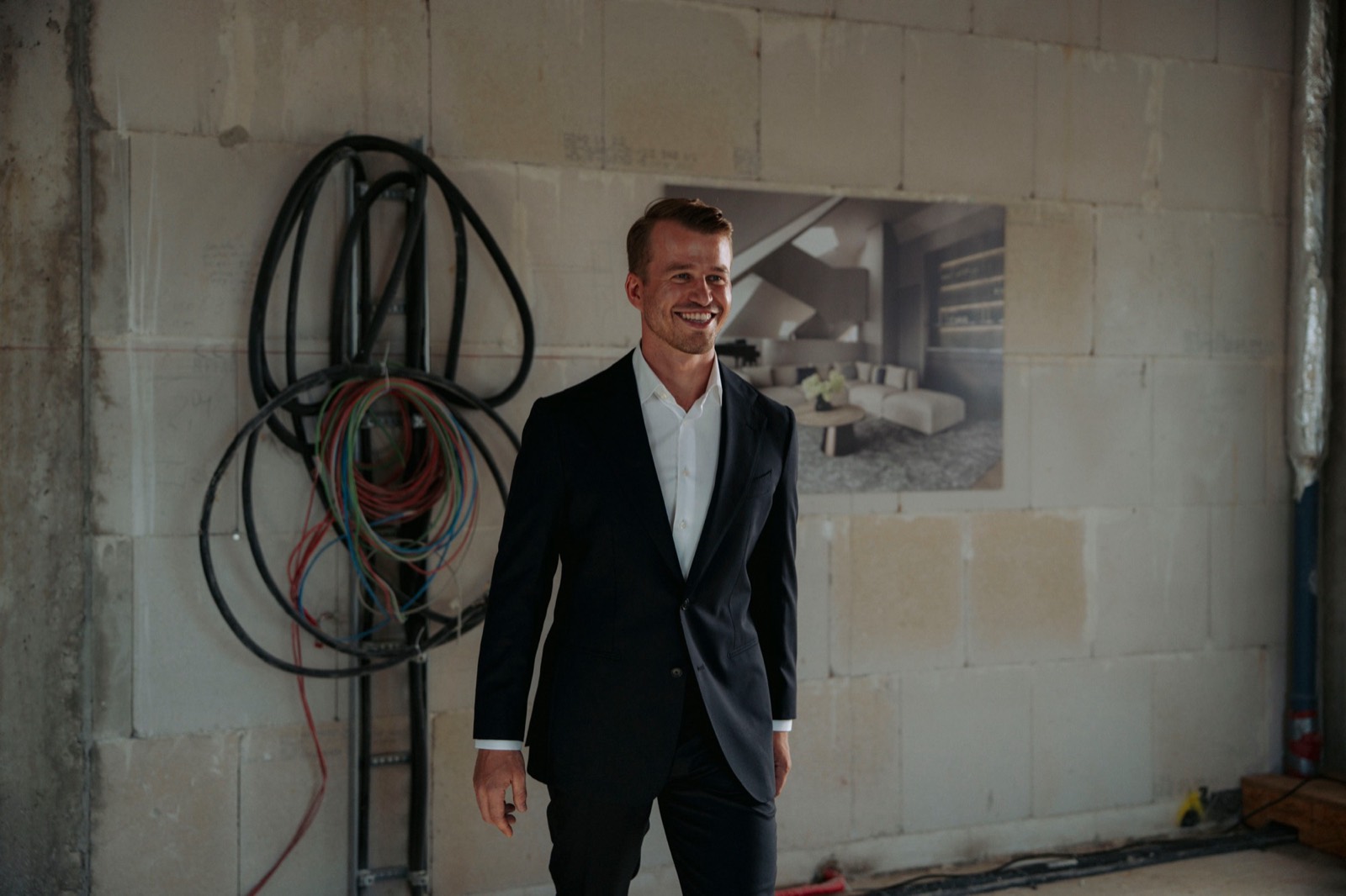 Daniel Hägele im Rohbau vor einer Wand mit Leitungen